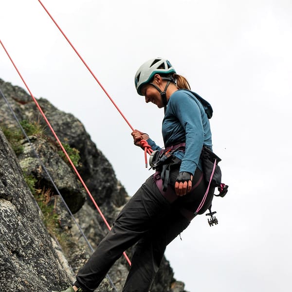 A WCA climber laughing as she leans back on her rope at a belay ledge